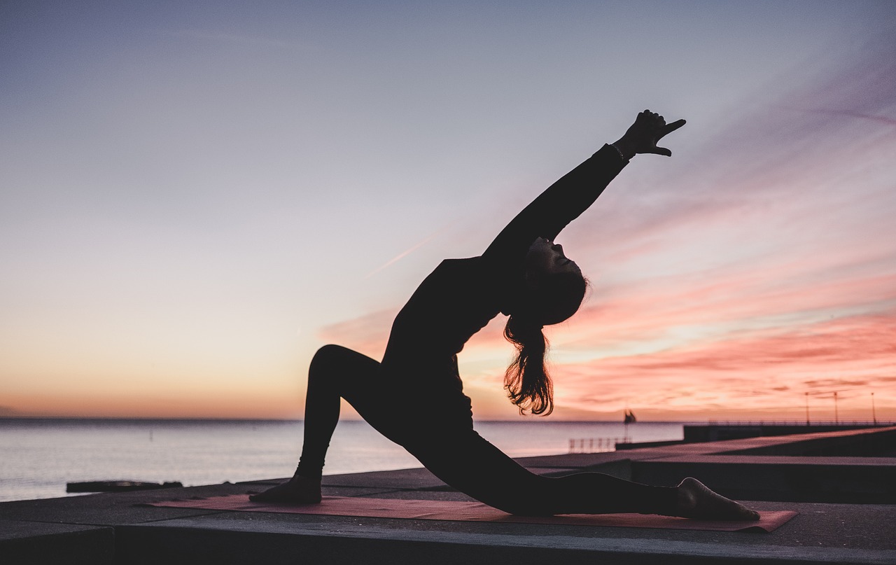 Mulher praticando ioga ao ar livre seguindo orientação de personal trainer online