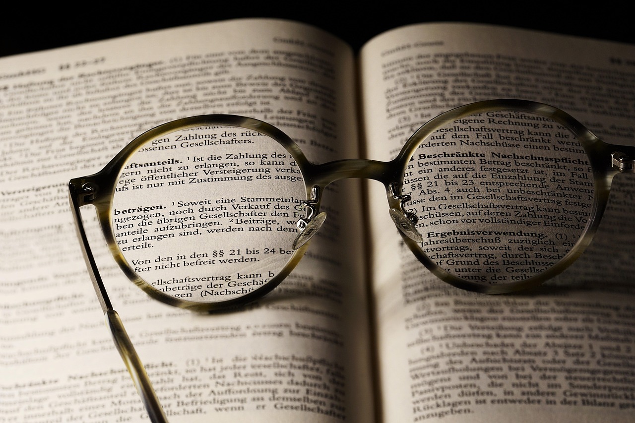 Livro aberto com óculos de leitura representando a revisão atenta de textos