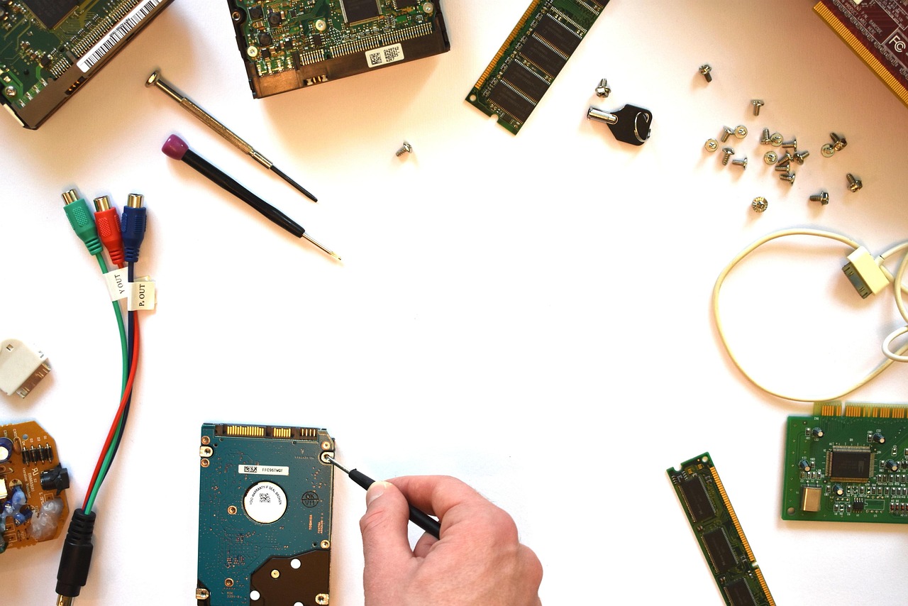 Técnico de informática realizando manutenção de computador com componentes de hardware sobre a mesa