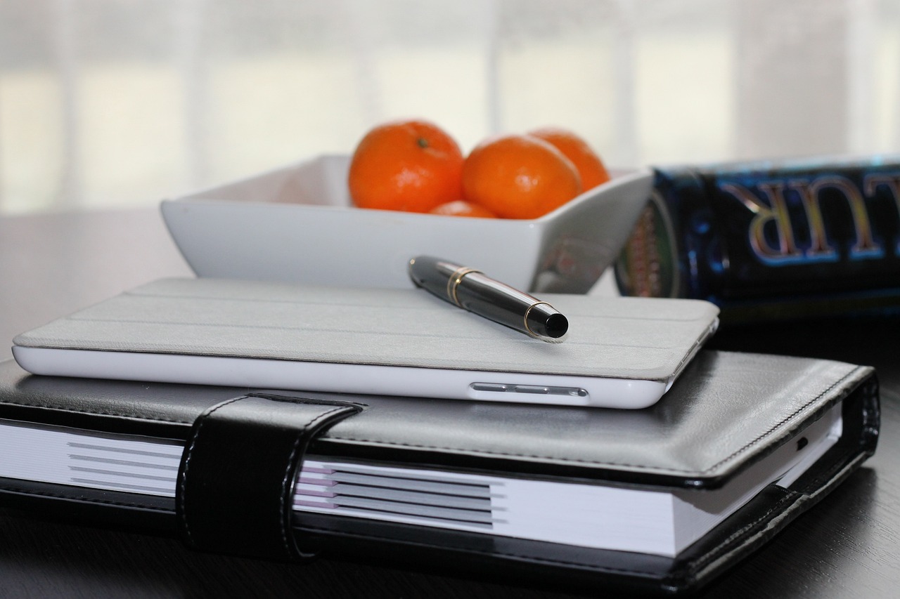 Caderno de planejamento com caneta e tablet para organizar tarefas e orçamento de assistente virtual